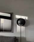 Modern black floor lamp in a minimalistic room with abstract art on the wall.