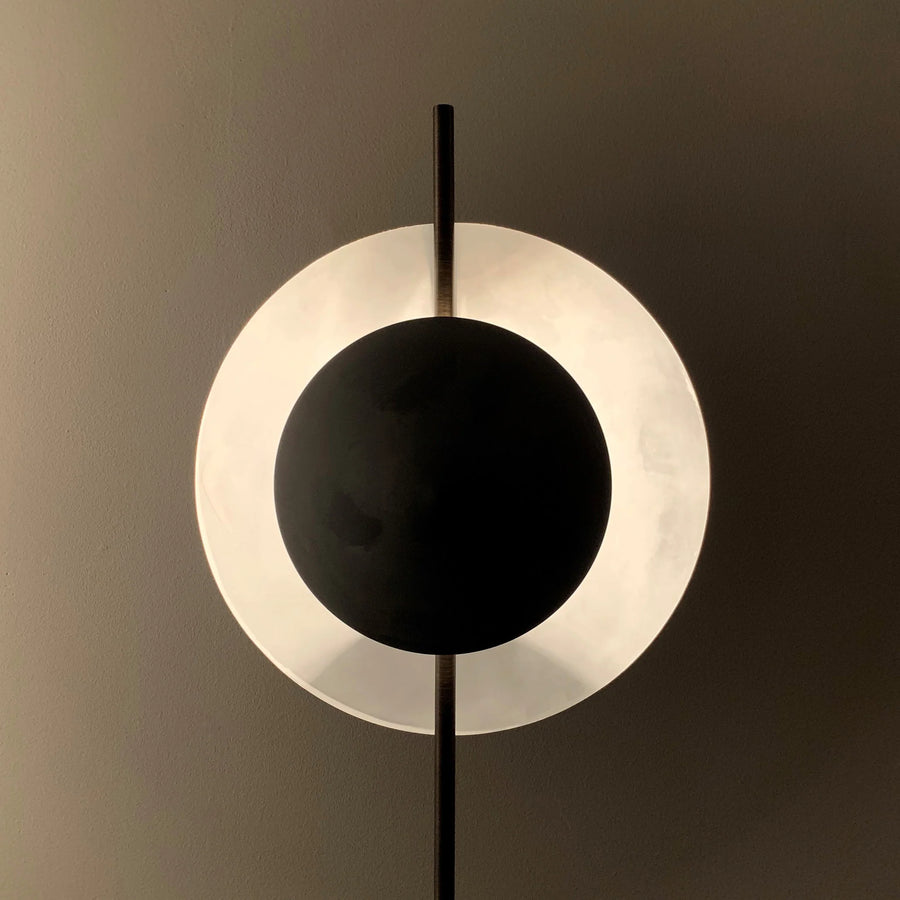 Modern wall lamp with black and white circular design on a dark background