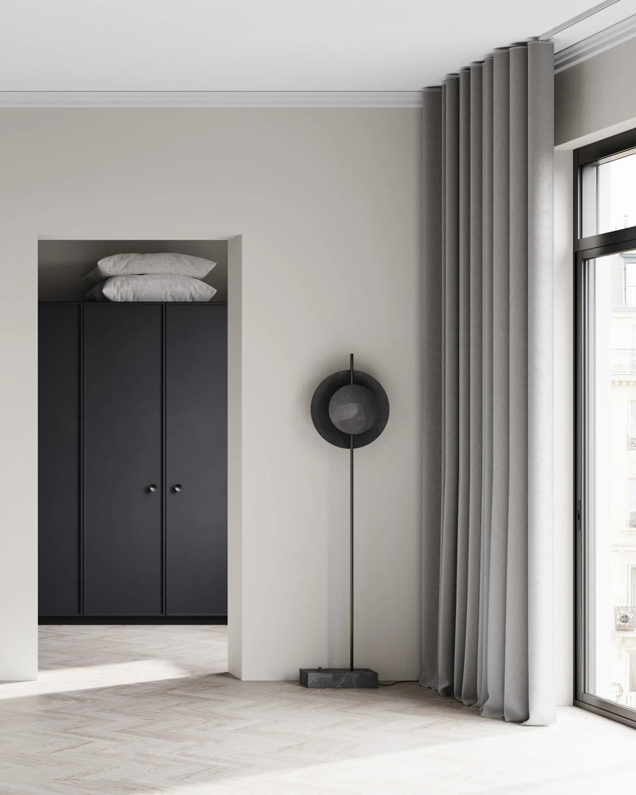 Modern interior with a black wardrobe, mirror, and floor lamp.