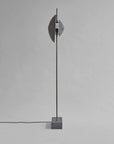 Modern floor lamp with concrete base and metallic shade on a gray background
