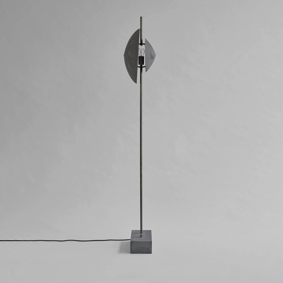 Modern floor lamp with concrete base and metallic shade on a gray background