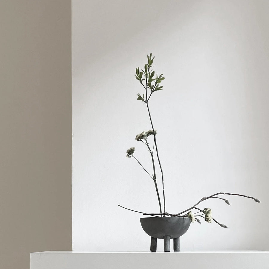Minimalist arrangement of branches in a small bowl against a neutral background from 101 Copenhagen at Spacio retail stores in Mumbai & Kolkata. 