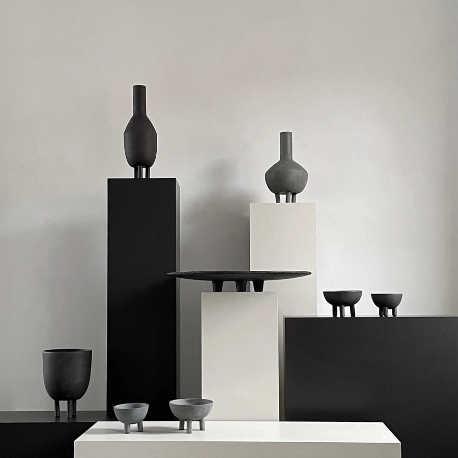 Collection of black ceramic vases and bowls on a neutral background from 101 Copenhagen at Spacio retail stores in Mumbai & Kolkata. 