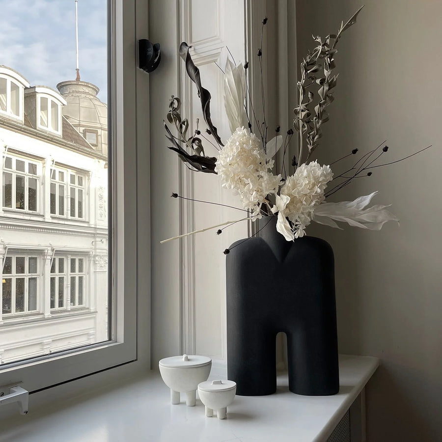 Decorative vase with flowers on a windowsill with cityscape view