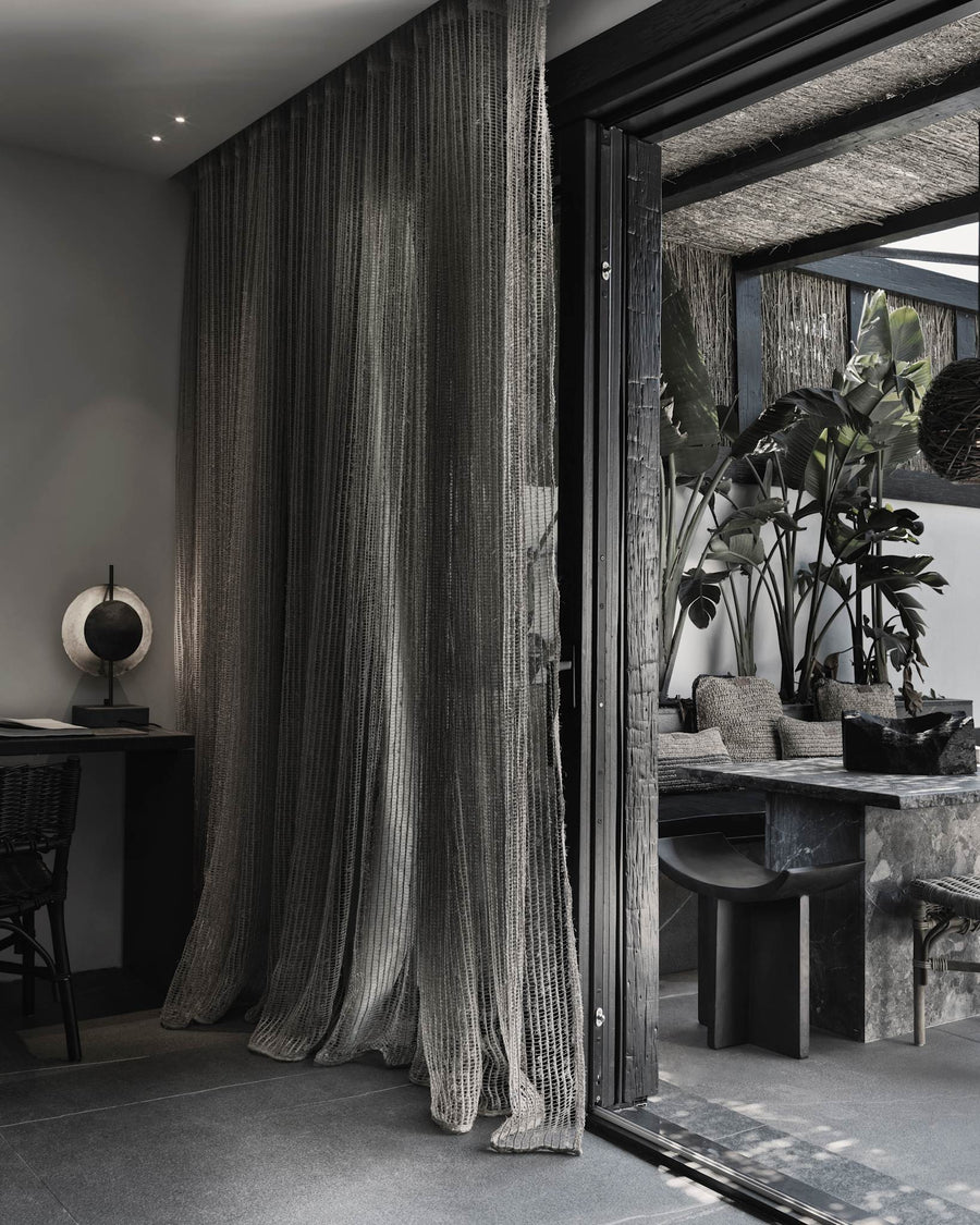 Modern interior with a large curtain and a glass door leading to an outdoor area.