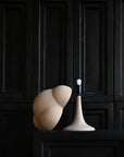 Modern white lamp with a black base against a dark paneled wall