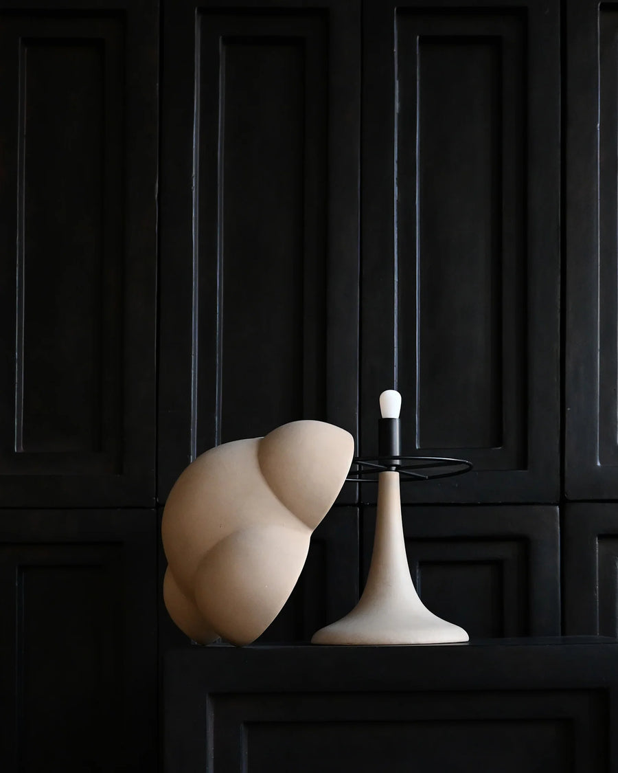 Modern white lamp with a black base against a dark paneled wall