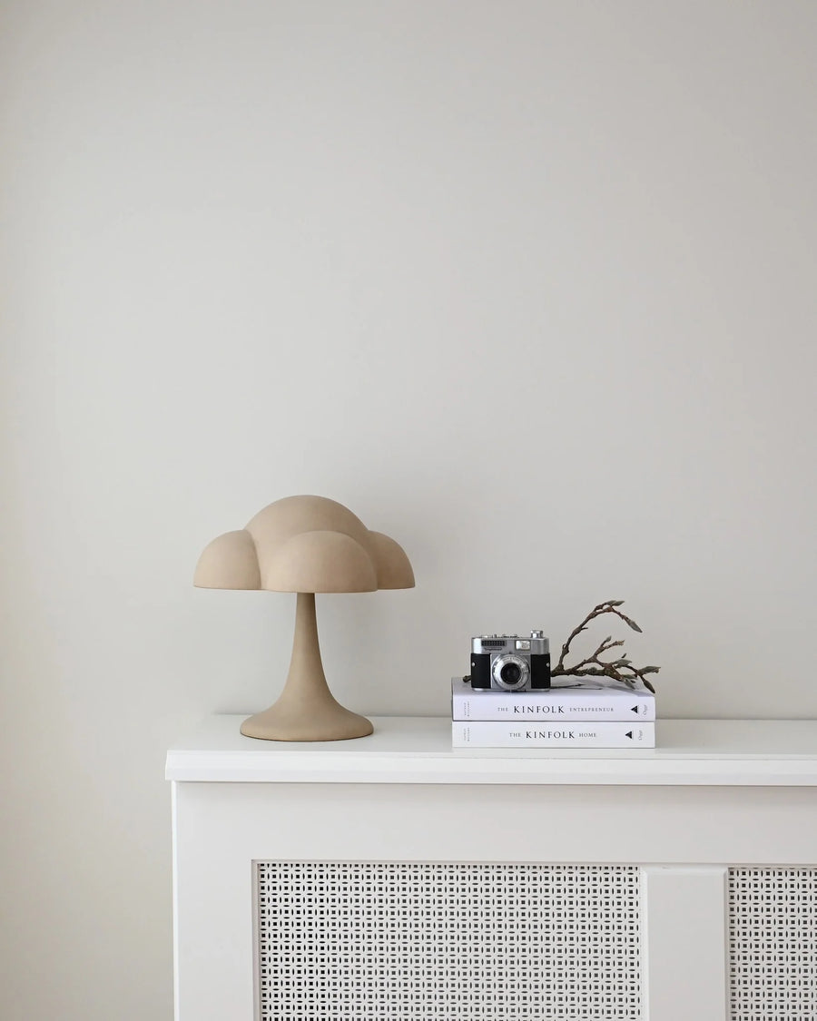 Beige cloud-shaped lamp on a white cabinet against a light gray wall