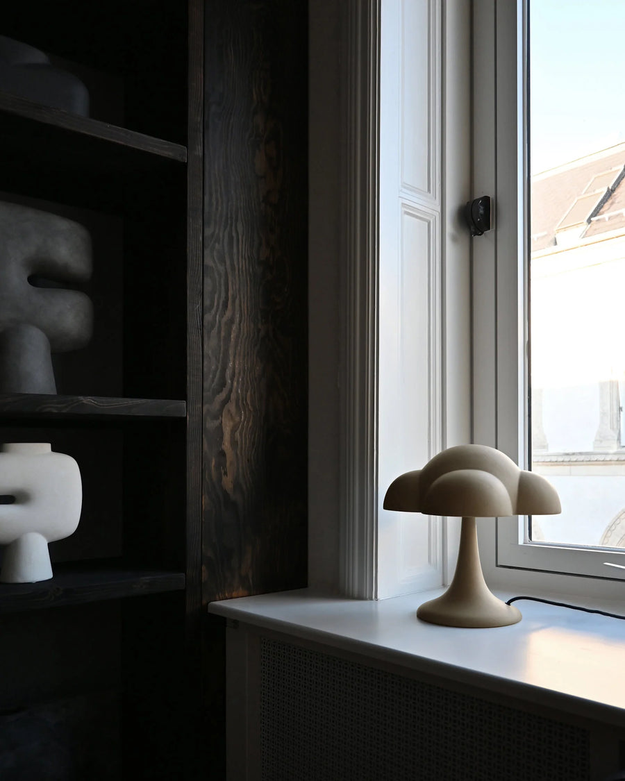 Decorative cloud-shaped lamp on a windowsill with a dark shelf in the background