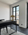 Modern office space with a desk, lamp, and large window.