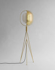 Brass floor lamp with a white shade on a gray background