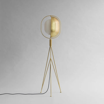 Brass floor lamp with a white shade on a gray background