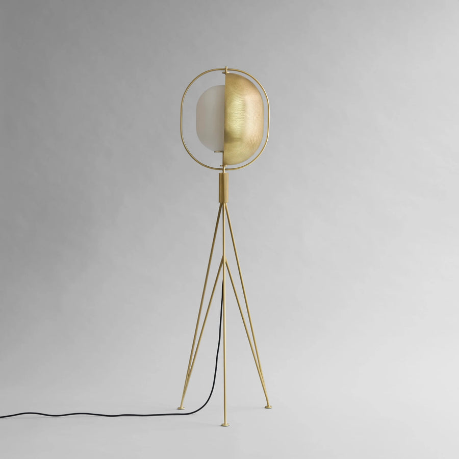 Brass floor lamp with a white shade on a gray background