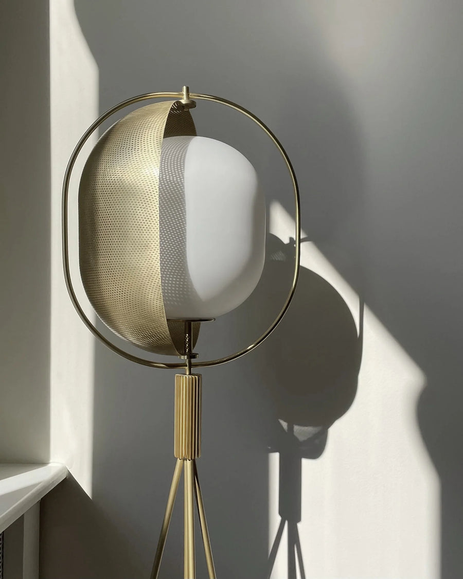 Modern floor lamp with gold and white design against a neutral wall