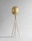 Brass floor lamp with a spherical shade on a gray background