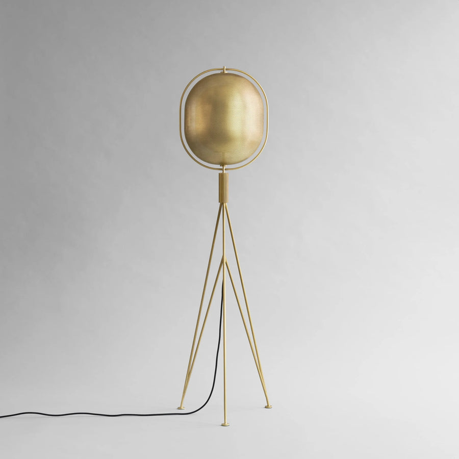 Brass floor lamp with a spherical shade on a gray background