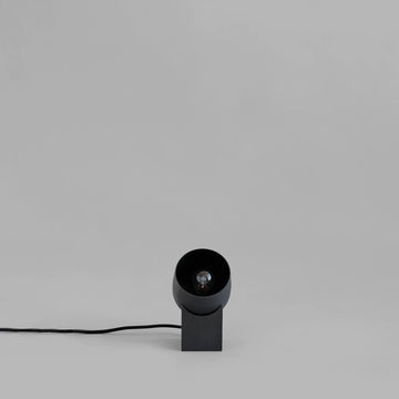 Minimal design Nordic Black table lamp on a light gray background from 101 Copenhagen available at Spacio retail stores in Mumbai & Kolkata. 