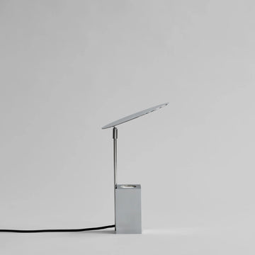 Modern silver desk lamp on a light gray background from 101 Copenhagen available at Spacio retail stores in Mumbai & Kolkata. 