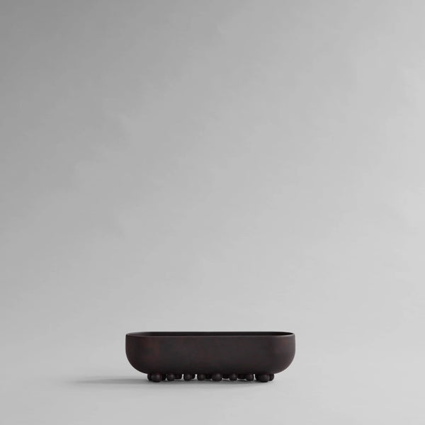 Black ceramic bowl on a gray background from 101 Copenhagen at Spacio retail stores in Mumbai & Kolkata. 