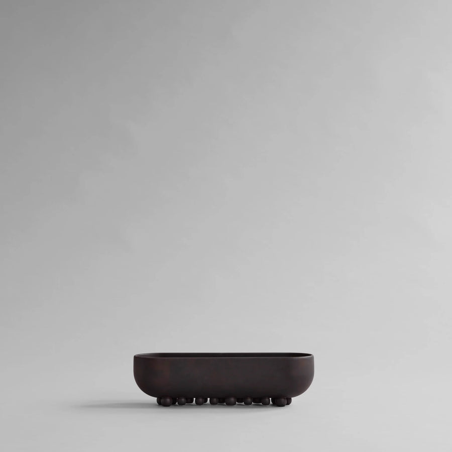 Black ceramic bowl on a gray background from 101 Copenhagen at Spacio retail stores in Mumbai & Kolkata. 