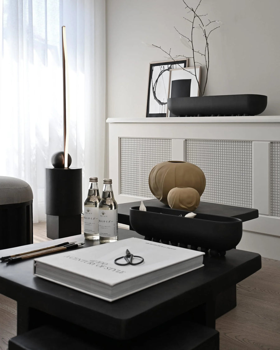 Modern interior with black table, decorative items, and a white wall.