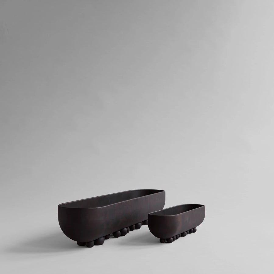 Two black ceramic planters on a gray background from 101 Copenhagen at Spacio retail stores in Mumbai & Kolkata. 