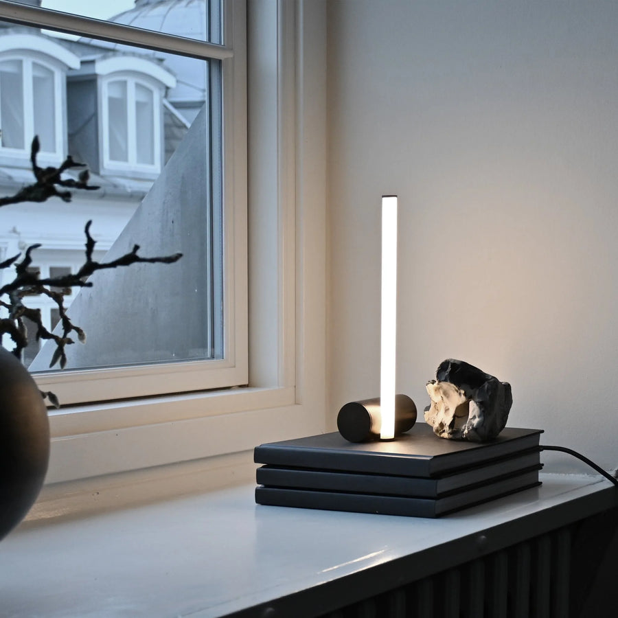 Modern table lamp with a rock-like base on a surface near a window