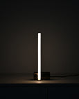 Modern table lamp with a long, thin light source on a dark background