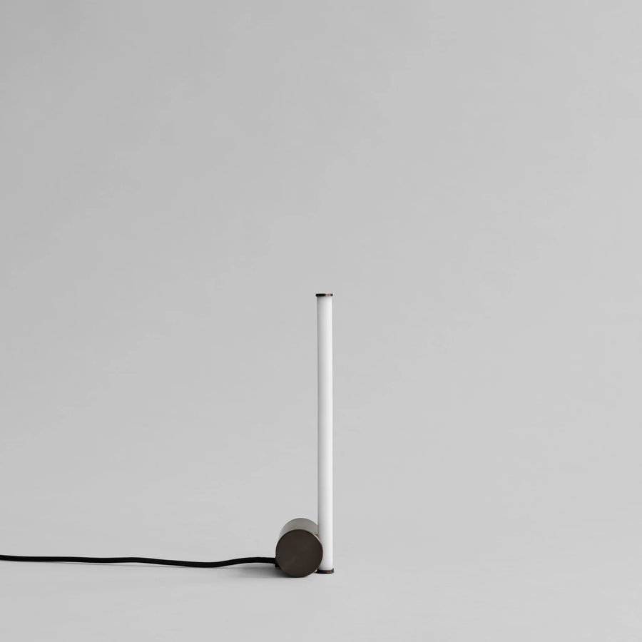 Modern pendant light with cylindrical shade and black cord on a gray background