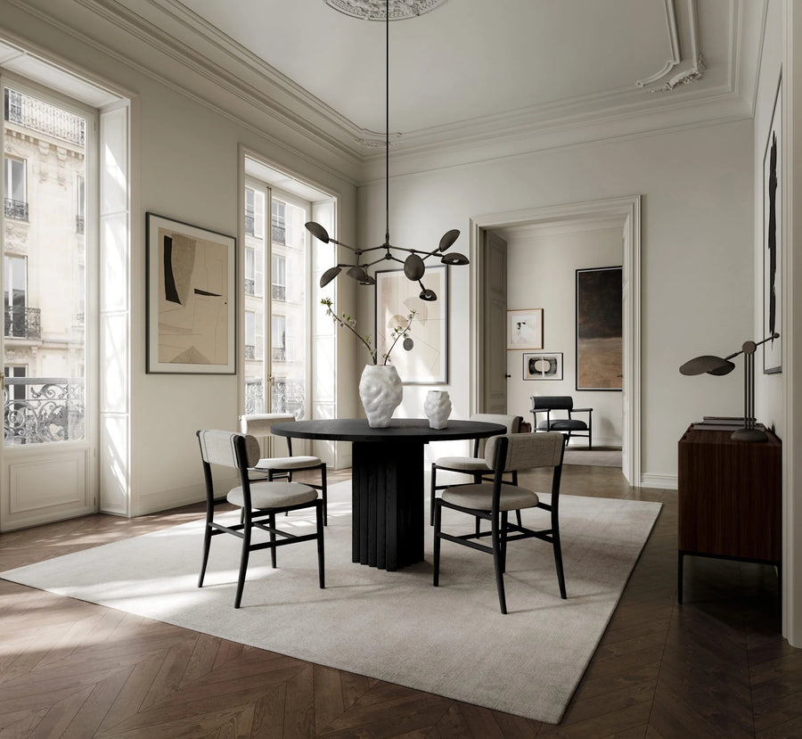 Modern minimalistic dining room with a black table and chairs, white walls, and large windows, chandelier and stingray table lamp from 101 Copenhagen available at Spacio retail stores in India
