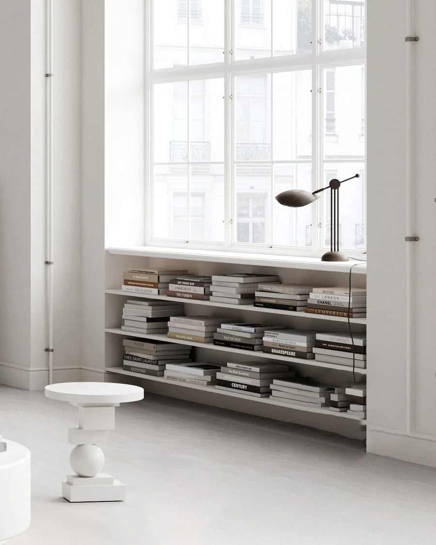 Bookshelf filled with books in a room with large windows and minimal decor.