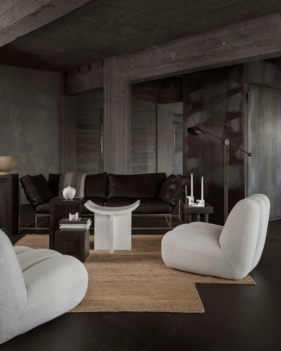 Modern living room with dark walls, a brown sofa, and light gray chairs.