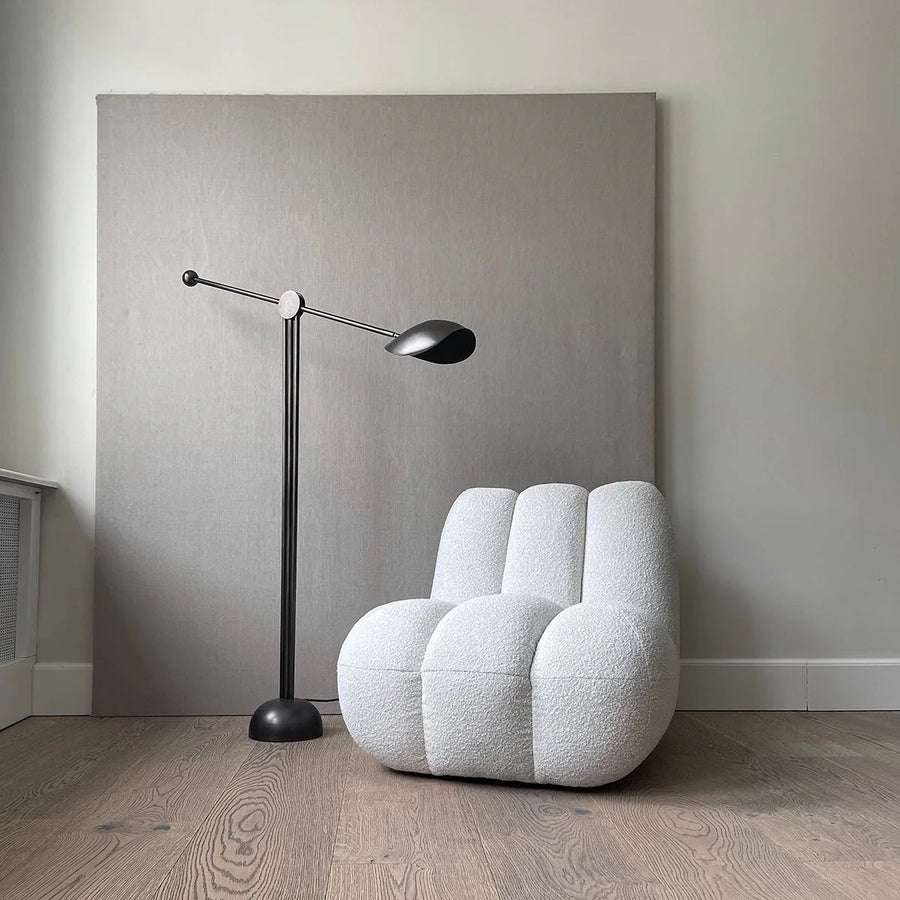 White textured chair and black floor lamp against a gray wall.