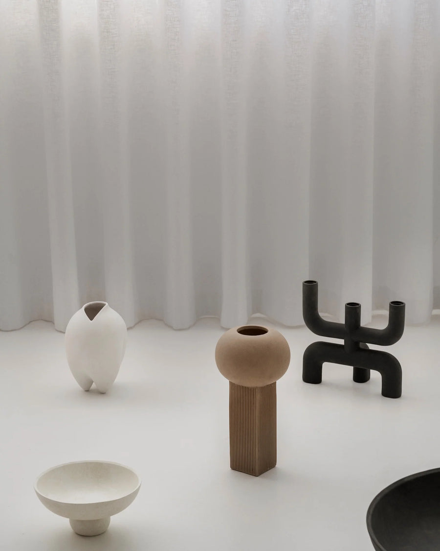 Set of modern vases on a white surface with a white curtain background
