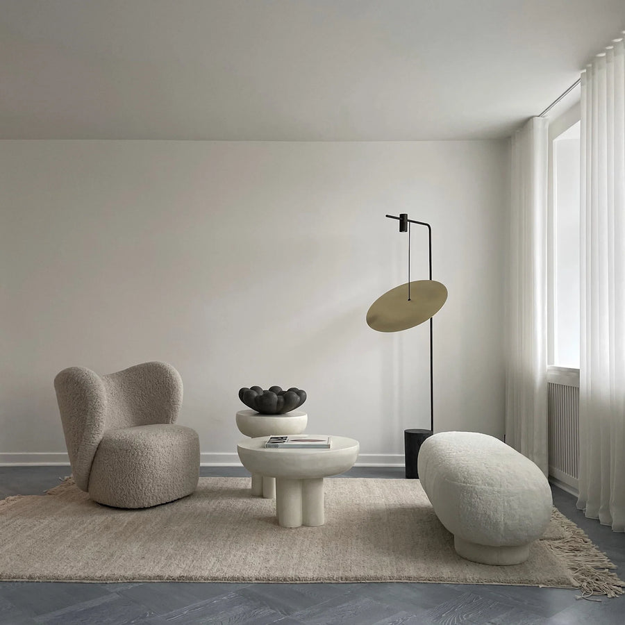 Modern living room with a minimalistic design featuring a chair, ottoman, and floor lamp.