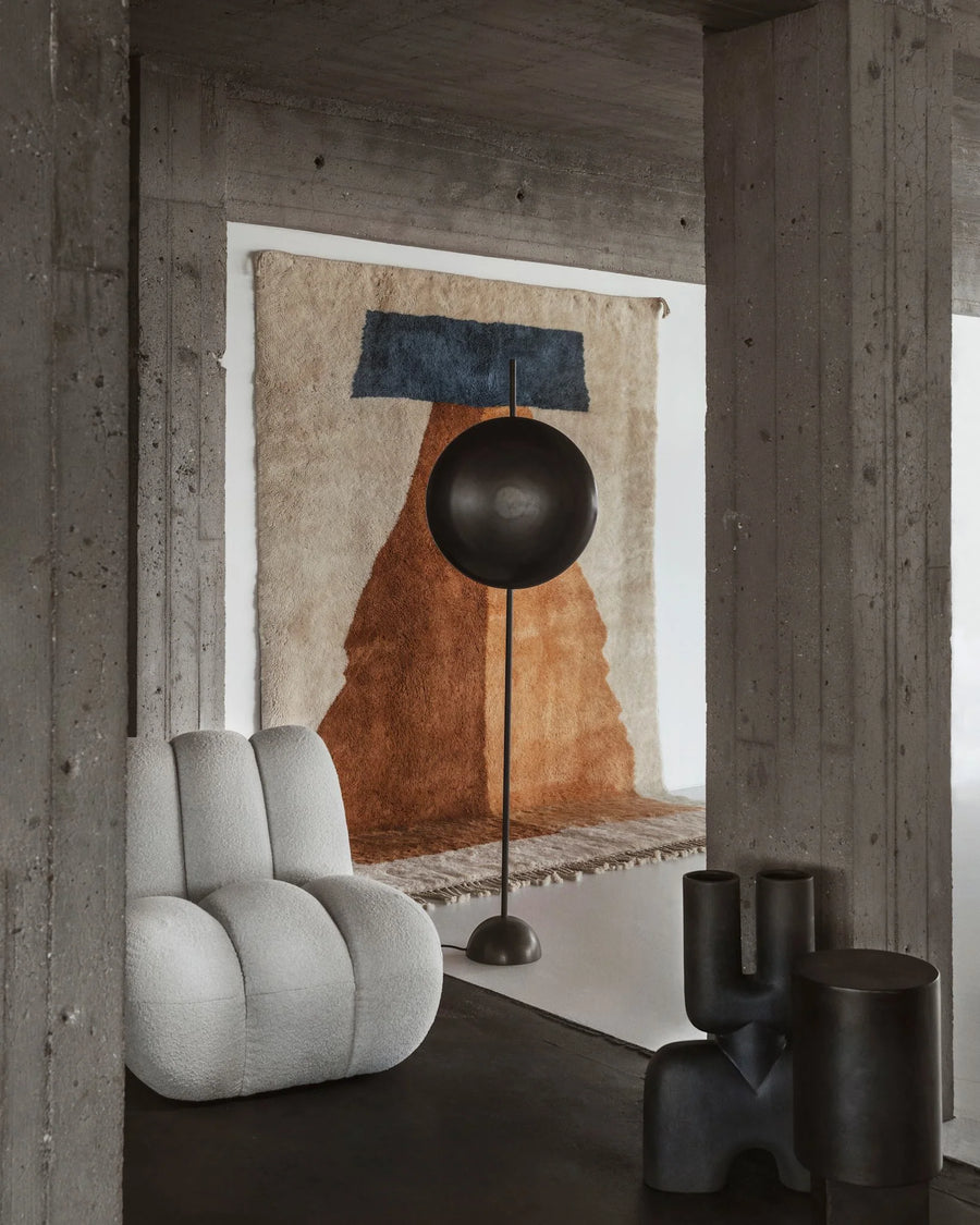 Modern interior with a gray armchair, black floor lamp, and abstract wall art.