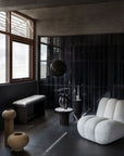 Modern interior with a white armchair, black wall, and decorative elements.