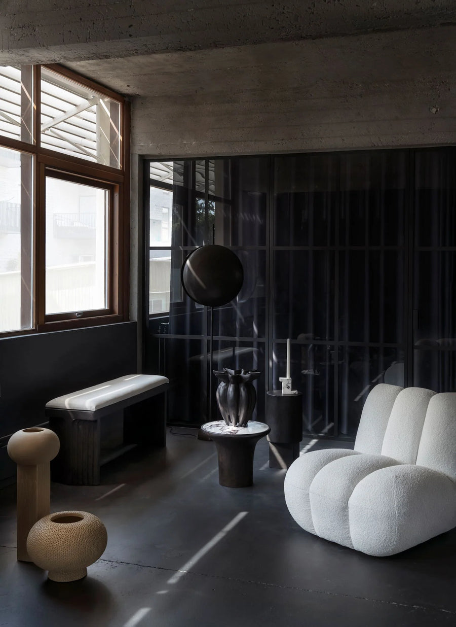 Modern interior with a white armchair, black wall, and decorative elements.