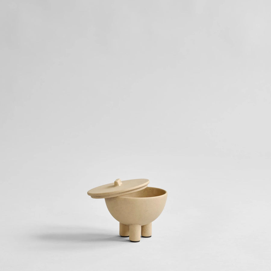 Beige ceramic container with lid on a light gray background from 101 Copenhagen at Spacio retail stores in Mumbai & Kolkata. 