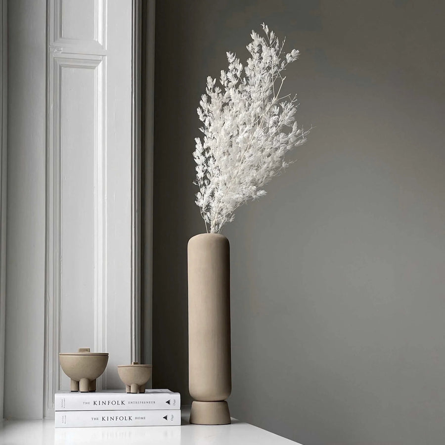 Beige vase with white dried flowers on a shelf with duck jars against a gray wall  from 101 Copenhagen at Spacio retail stores in Mumbai & Kolkata. 