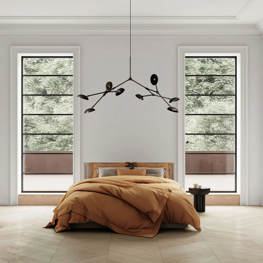 Modern bedroom with a bed, chandelier, and large windows.