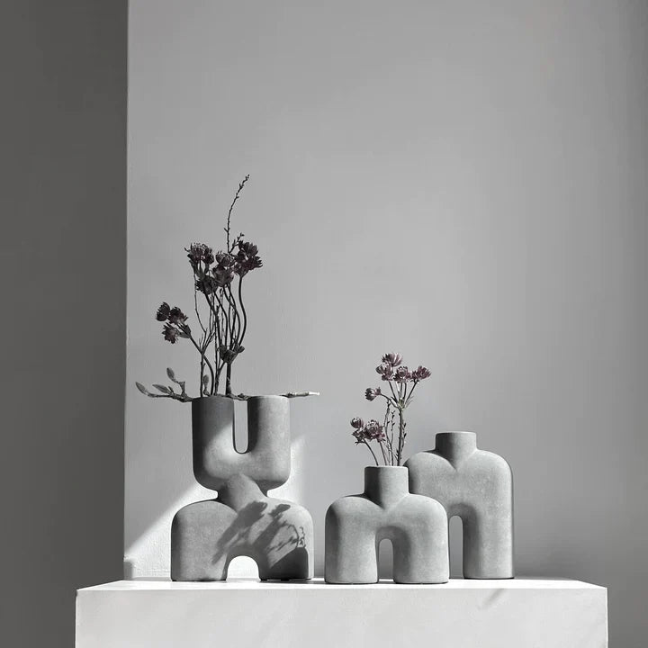 Three 101Cph Cobra Tall Mini Dark Grey 211034 vases sitting on a table in front of a white wall.