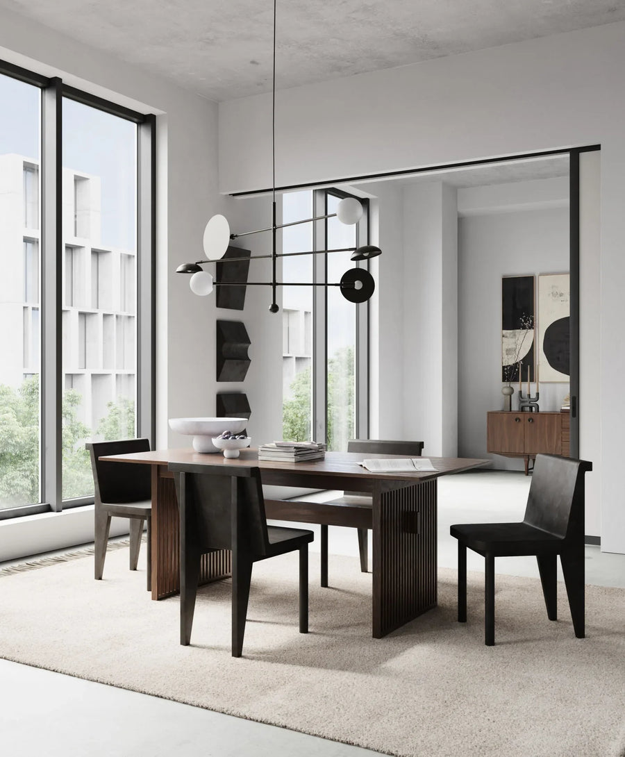 A modern dining table and chairs in a room with large windows. The dining set features the 101Cph Empire Mini Dark Grey 223036 table, which is made of ceramic and comes in a stylish dark grey color.