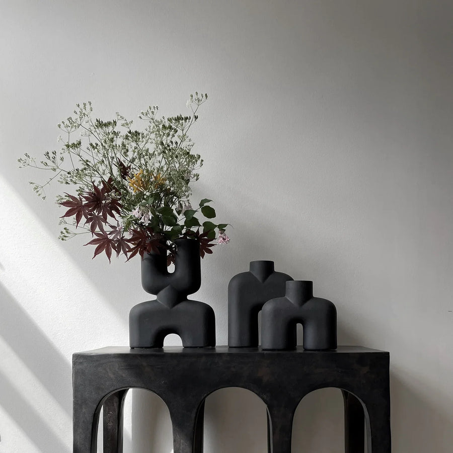 Two 101 Copenhagen Cobra Double Mini Coffee 212002 vases sit on a table in an interior setting, in front of a white wall.