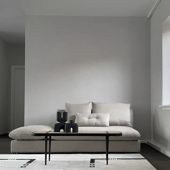 A living room with a 101Cph Cobra Uno Mini Black 203024 couch and a white rug decorated with quirky vases by 101 Copenhagen.
