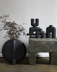 A group of 101Cph Cobra Uno Mini Black 203024 vases on a table next to a plant by 101 Copenhagen.