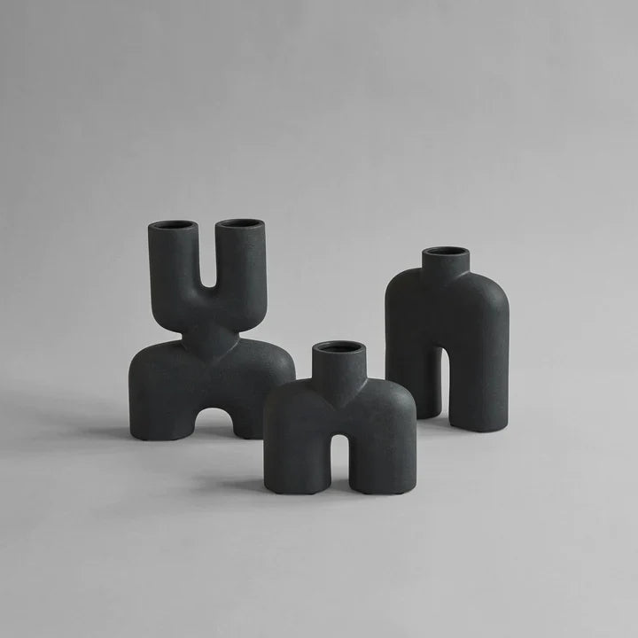 Three quirky vases, including the 101Cph Cobra Uno Mini Black 203024 by 101 Copenhagen, in black color, placed on a grey surface.