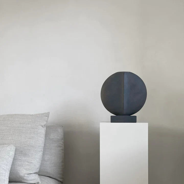 A quirky table lamp on a pedestal next to a couch featuring the 101Cph Guggenheim Mini Coffee 111220 from 101 Copenhagen.