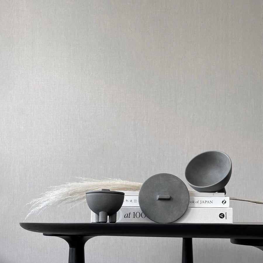 Three gray ceramic bowls on a black table against a light gray wall from 101 Copenhagen at Spacio retail stores in Mumbai & Kolkata. 