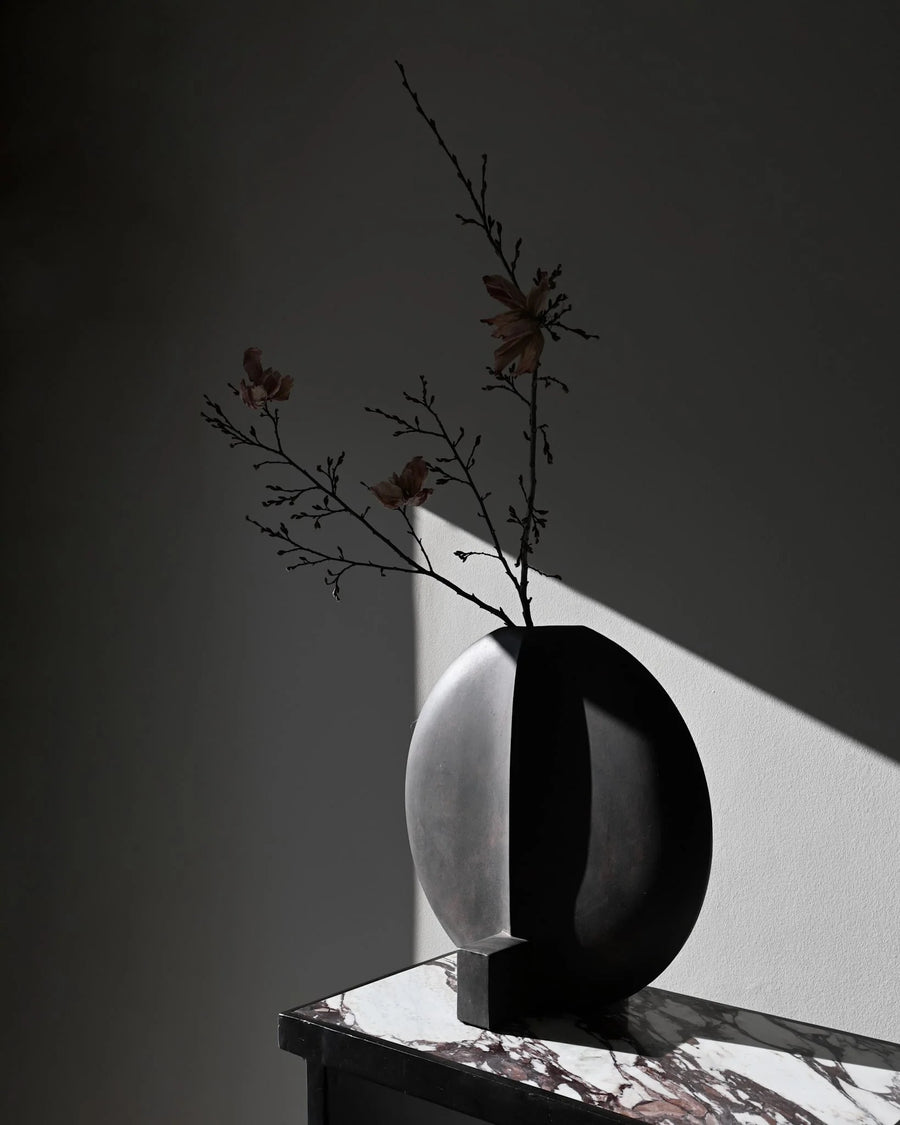Black and white vase with branches styled on a Fibre concrete and calacatta marble top console from 101 Copenhagen at Spacio retail stores in Mumbai & Kolkata. 